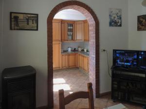 a kitchen with an archway in a room with a television at Villetta il Camuciolo in Torre del Lago Puccini