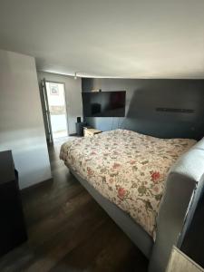 a bedroom with a bed with a floral bedspread at Maison à la campagne in Mecquignies
