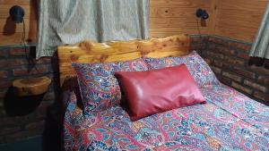 a bed with a wooden head board and a red pillow at Cabañas del Bosque Bariloche in San Carlos de Bariloche