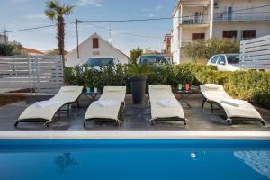un gruppo di sedie a sdraio accanto a una piscina di Villa Sara a Vodice