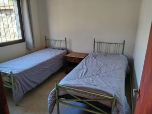 two beds in a small room with a night stand at Casa nueva en Daymán in Termas del Daymán