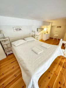 a large white bed in a room with wooden floors at Roula's Suites in Andros