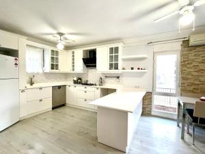 a white kitchen with white cabinets and a table at Triplex Family House, Kusadasi in Kuşadası