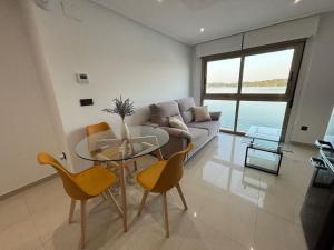 a living room with a glass table and yellow chairs at El Capricho de la ría II in O Grove