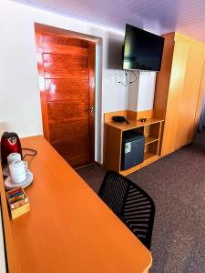 a room with a table and a desk with a television at Andenes del Inca Hotel in Ollantaytambo