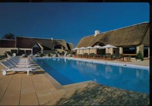 a swimming pool with lounge chairs and a building at Écrin Neuf au Cœur du Golf in Saint-André-des-Eaux