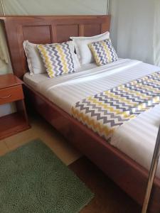 1 cama con cabecero de madera y almohadas en Impala Suites Jinja, en Jinja