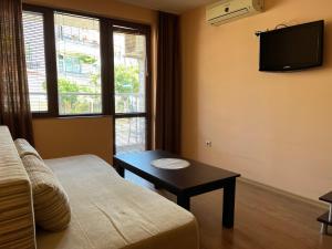 a living room with a couch and a table and a tv at Hotel Silver in Sozopol