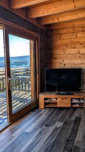 a living room with a television and a large window at Chalet Cosy avec vue imprenable sur le lac in La Celle-sous-Gouzon