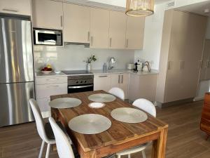 a kitchen with a wooden table and white cabinets at Gandia Playa Moderna - nuevo con piscina y parking, 2 banos, playa 300 m, grau 300 m in Playa de Gandia +50 photos