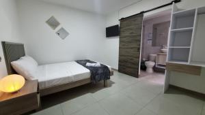 a bedroom with a bed and a bathroom with a toilet at Hotel Fuente Real in Popayan