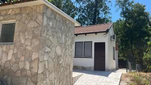 a house with a stone wall next to a garage at Green Trebižat Nature Stay in Čapljina