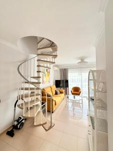 Una escalera de caracol en una sala de estar con un sofá amarillo. en Sunny penthouse in Golf del Sur, en San Miguel de Abona