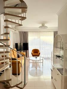 una sala de estar con una escalera de caracol y una mesa en Sunny penthouse in Golf del Sur, en San Miguel de Abona