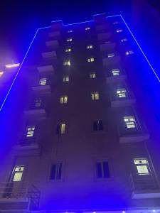 a tall building with lit windows at night at Elegance suiets hotel Almangaf إليغانس للشقق الفندقية المنقف in Kuwait