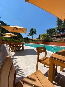 a swimming pool with tables and umbrellas and a pool at Granja del Cafe Hotel y Centro de convenciones in Venecia