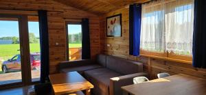 a living room with a couch and a table and windows at Domek nad jeziorem Weekend in Swiętajno