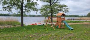a playground with a slide next to a lake at Domek nad jeziorem Weekend in Swiętajno