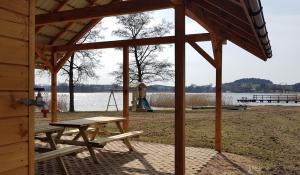 a wooden pavilion with a picnic table next to a lake at Domek nad jeziorem Weekend in Swiętajno