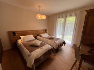 two beds in a room with a window at Gîtes du Grand Replomb, Les Artistes, Piscine et Jacuzzi in Sainte-Agnès
