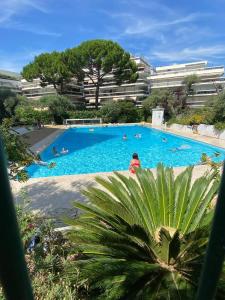 a large swimming pool with people swimming in it at Le lys d'or Piscine Plage Terrasse Wiffi in Juan-les-Pins