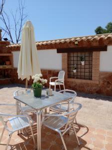 una mesa de patio con sombrilla y sillas en CORTIJO Rural MOLINO EL TARAHAL con piscina y zonas compartidas, en El Tarahal