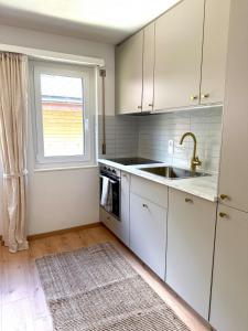 a kitchen with white cabinets and a sink and a window at Gorgeous Modern Mountain View Flat in Täsch with free parking in Täsch +32 photos