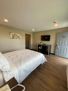 a bedroom with a white bed and a flat screen tv at Four Seasons Inn in Gallipolis