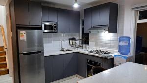 a kitchen with black cabinets and a stainless steel refrigerator at Cabin with an ocean view in Coquimbo