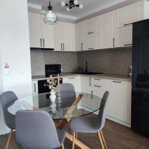 eine Küche mit Glastisch und weißen Schränken in der Unterkunft Апартамент "Rodopi" с Гледка към Езеро Безплатен Подземен Гараж in Smoljan