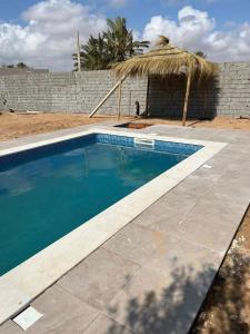 a swimming pool with a straw umbrella next to a wall at Riad Houch Amine B&B in Midoun +25 photos
