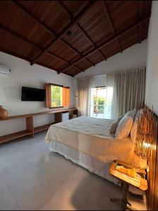a bedroom with a large bed and a television at Almaré Hospedagem - Boipeba in Cayru