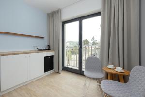 a living room with a table and chairs and a balcony at Na Fali Restaurant&Apartaments in Pobierowo