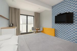 a hotel room with a bed and a tv on a wall at Na Fali Restaurant&Apartaments in Pobierowo