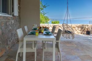 a white table and chairs on a patio with the ocean at Morska vila Sanja in Starigrad-Paklenica