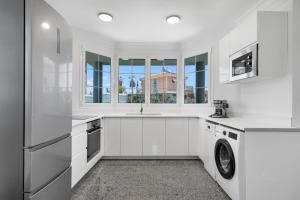 a white kitchen with a sink and a dishwasher at Villa Edén House by Maspalomas Holiday Villas in Maspalomas