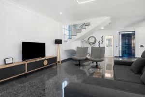 a living room with a tv and a couch and chairs at Villa Edén House by Maspalomas Holiday Villas in Maspalomas