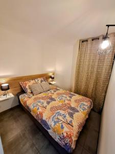 a bedroom with a bed with a colorful blanket at Entre Terre et Mer, logement cosy in Poussan