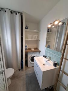 a bathroom with a sink and a washing machine at Entre Terre et Mer, logement cosy in Poussan