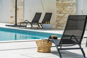 Un grupo de sillas junto a una piscina. en Villa 65 Large 55m2 Private Heated Pool Peaceful Escape, en Škabrnje