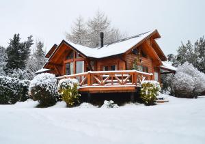 una cabaña de troncos con nieve en el techo en Guardianes Del Bayo, en Villa La Angostura