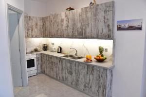 a kitchen with wooden cabinets and a sink at Mitsakos Golden Villa in Egina +35 photos