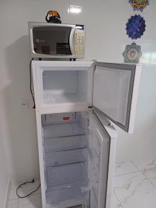 a refrigerator with a microwave on top of it at Casinha top perto Águas Quentes in Barra do Garças