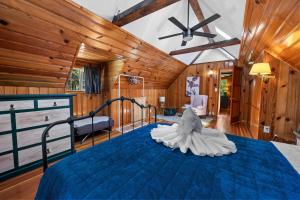ein Schlafzimmer mit einem blauen Bett in einem Zimmer mit Holzwänden in der Unterkunft Bear Cub Cabin with Hot Tub, Outdoor Patio w BBQ! in Big Bear City Airport