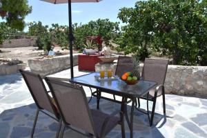 a table and chairs with an umbrella and a bowl of fruit at Mitsakos Golden Villa in Egina