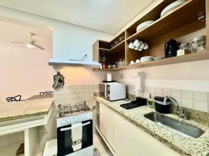 een keuken met een spoelbak en een fornuis bovenste oven bij Condôminio Latitude 23 - Ubatuba in Ubatuba