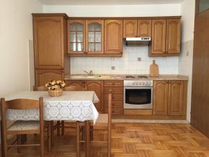 a kitchen with wooden cabinets and a table with chairs at Apartments Antonia in Malinska
