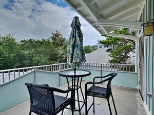 a patio table with two chairs and an umbrella on a balcony at Sand Piper in Seacrest