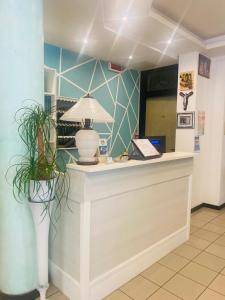 a lobby with a counter with a lamp and plants at Hotel Criniera D'oro in Rimini