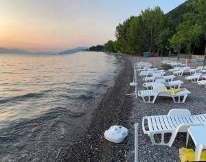 a row of white chairs on a beach next to the water at Studio Tamara in Ohrid